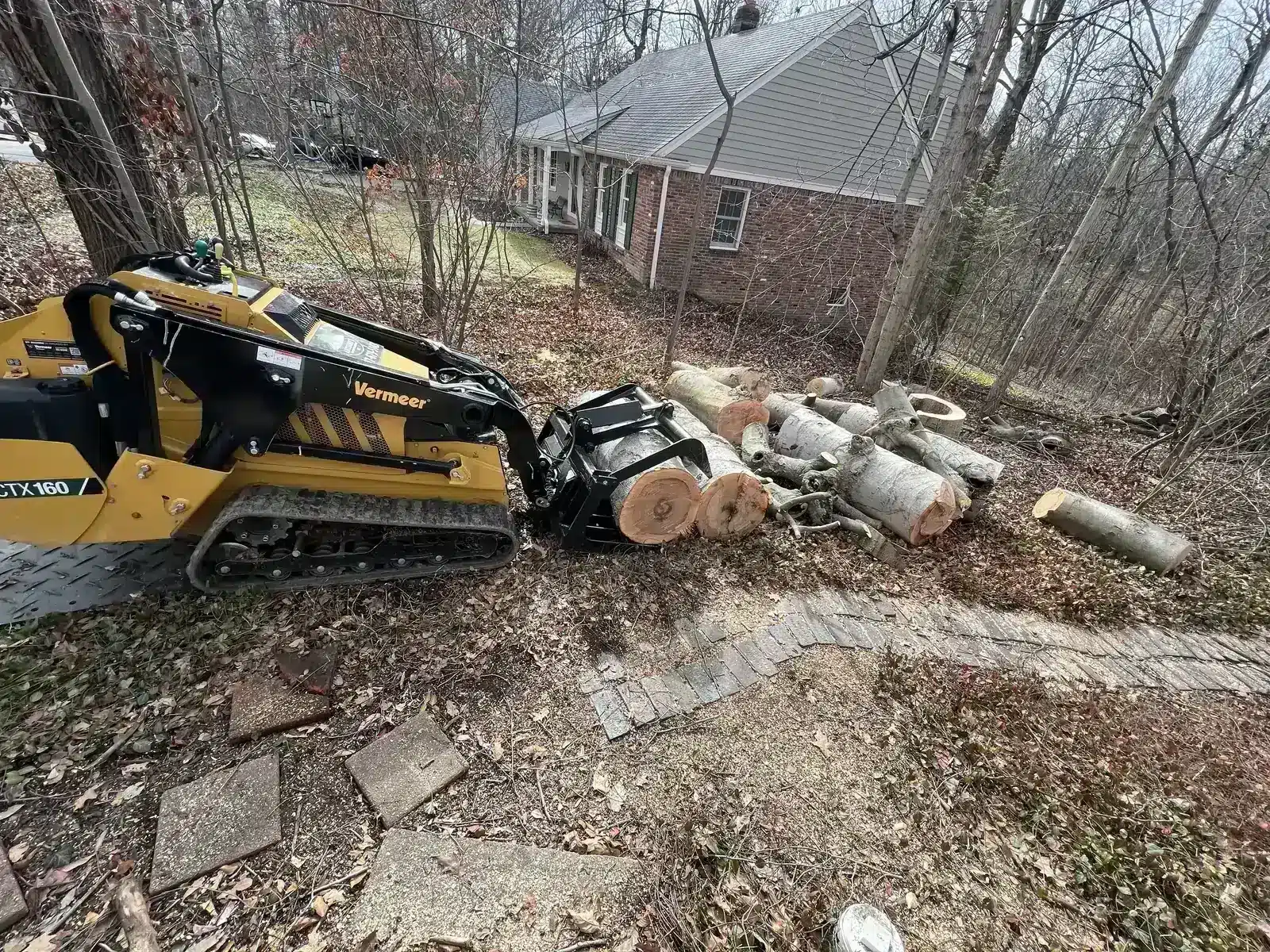 Mini skid steer hauling logs off a lot in Carmel, IN