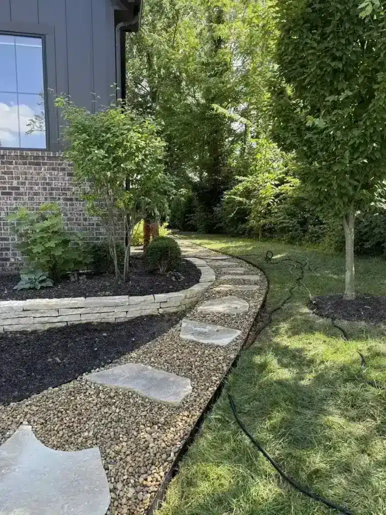 Stone and paver path with gravel beside a dark modern home