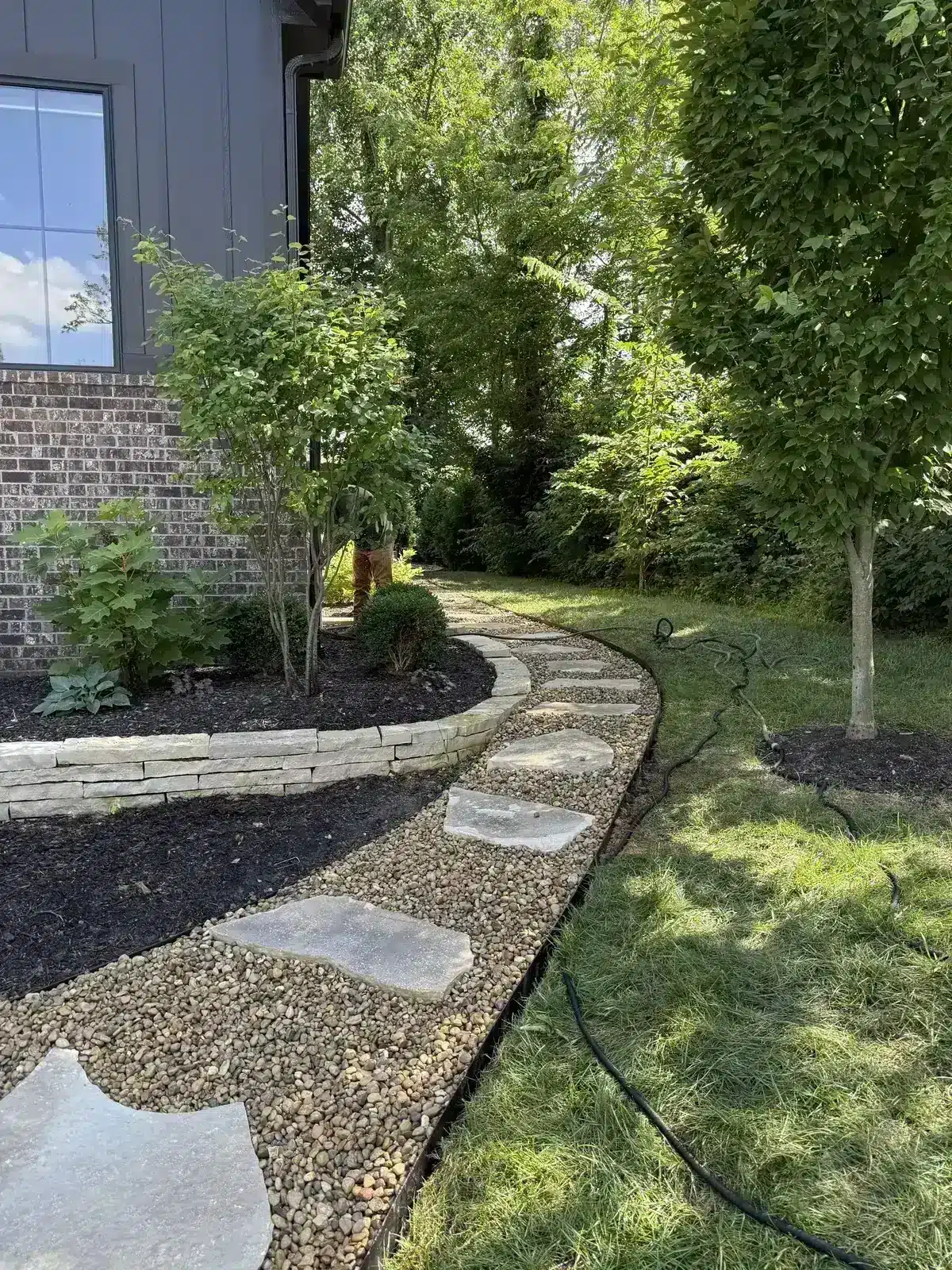 Stone and paver path with gravel beside a dark modern home, serving Westfield, IN